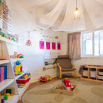 Nursery room with fabric canopy, colorful storage, reading nook, and natural light at Albany childcare centre