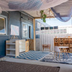 Covered outdoor learning space with wooden furniture, fabric canopy, and educational posters at Albany childcare centre