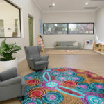 Bright, welcoming parent lounge with Indigenous art floor mat at Brabham childcare centre"
