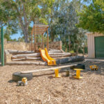 Natural outdoor play space with climbing structure and slide at East Cannington childcare