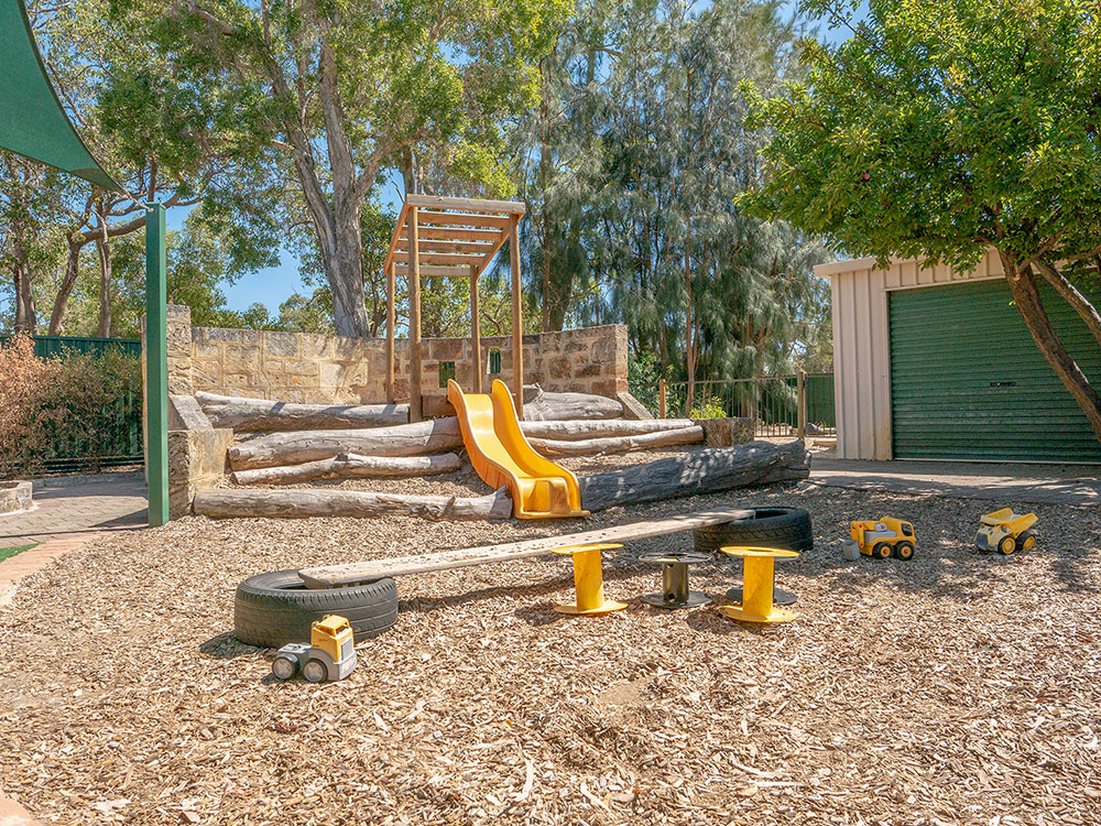 Natural outdoor play space with climbing structure and slide at East Cannington childcare