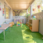 Covered outdoor play area with artificial turf and activity stations at East Cannington childcare