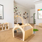 Infant play area with climbing equipment and family photos at Kalgoorlie childcare centre