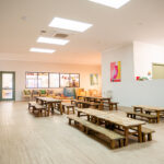Sun-lit dining area with timber tables and benches at Kalgoorlie childcare centre
