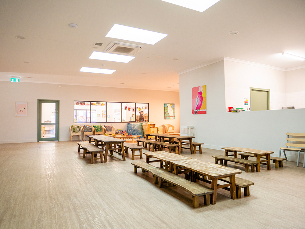 Sun-lit dining area with timber tables and benches at Kalgoorlie childcare centre
