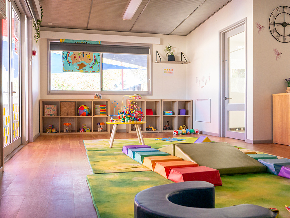 Bright infant room with soft play equipment and developmental toys at Newman childcare centre