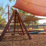 Timber climbing frame with shade sails in natural outdoor environment at Newman centre