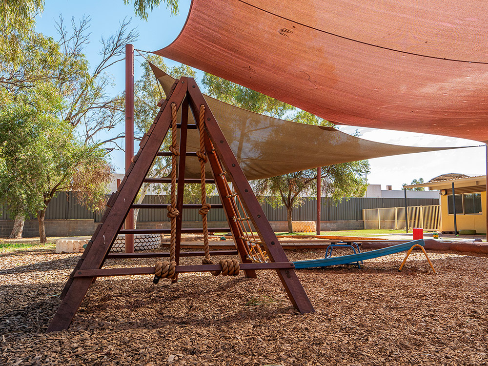 Timber climbing frame with shade sails in natural outdoor environment at Newman centre