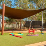 Shaded outdoor play space with natural features and sensory activities at Newman centre