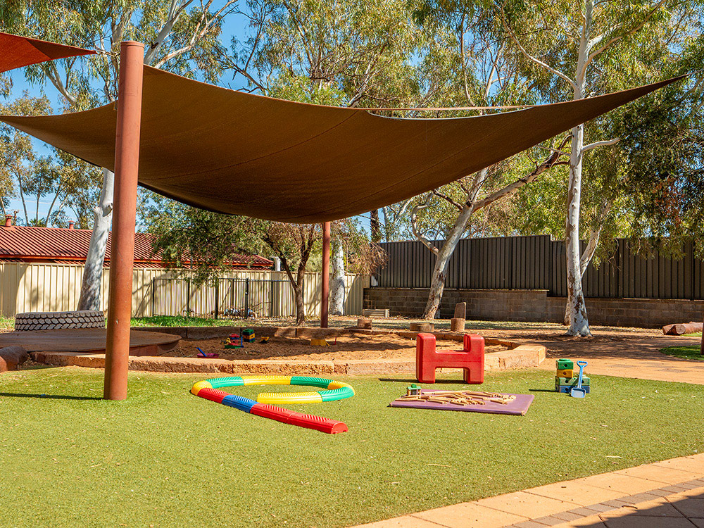 Shaded outdoor play space with natural features and sensory activities at Newman centre