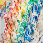 Close-up of rainbow-colored handprint art display showing children's creative work at Gumtrees OSHC