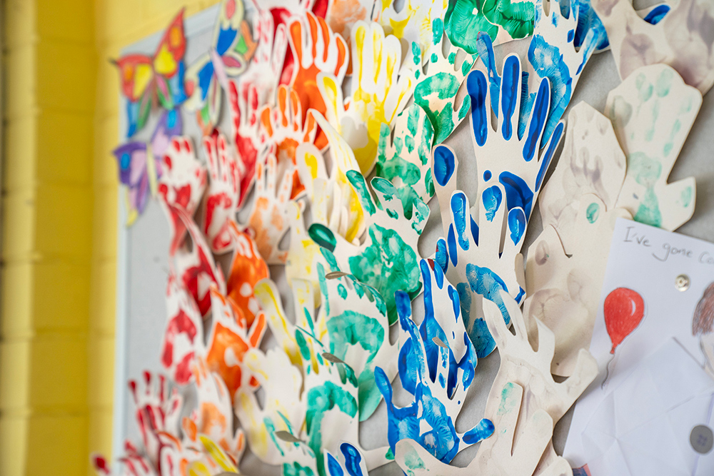 Close-up of rainbow-colored handprint art display showing children's creative work at Gumtrees OSHC