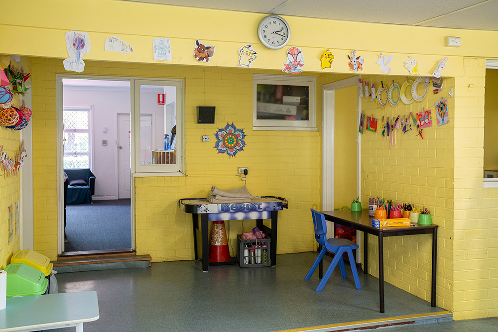 Bright yellow classroom at Gumtrees OSHC Service with children's artwork on walls, activity stations, and furniture