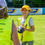Smiling child holding football during Coles Healthy Kicks activity at Gumtrees School Holiday Program