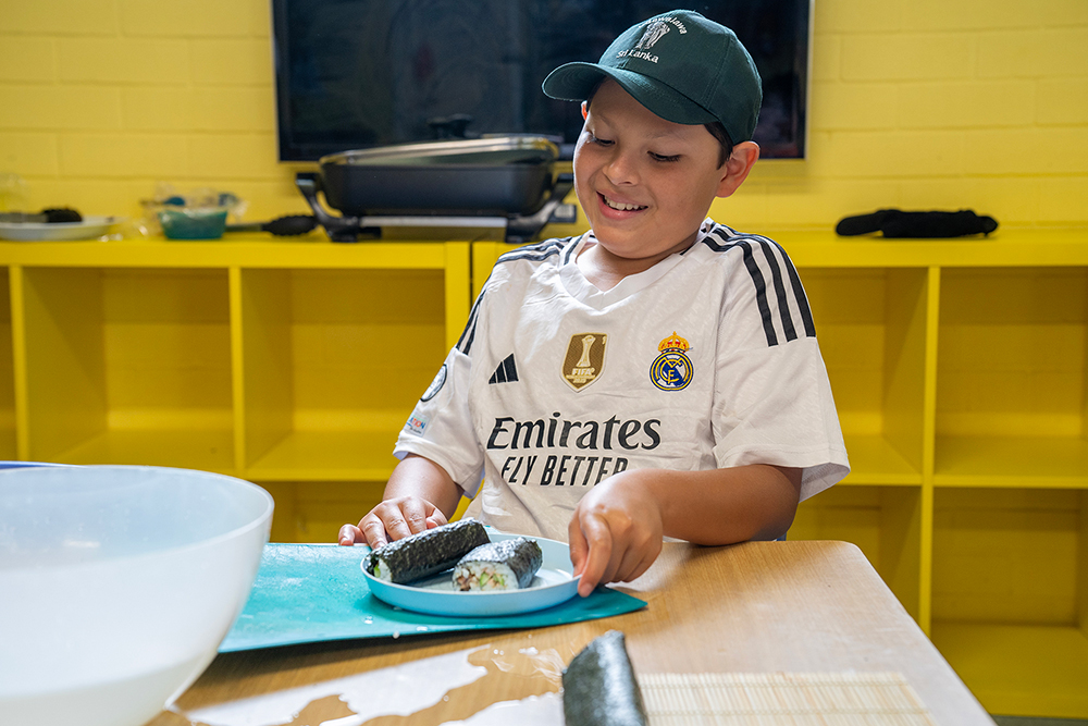 Child arranging homemade sushi on plate during cooking activity at Gumtrees OSHC School Holiday Program