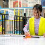 Child playing air hockey at Huntingdale OSHC School Holiday Program