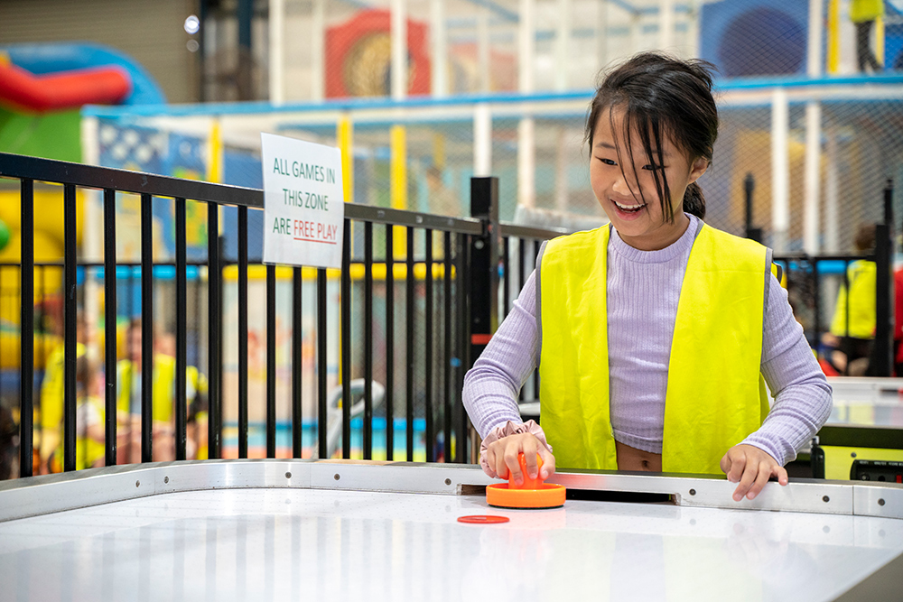 Child playing air hockey at Huntingdale OSHC School Holiday Program