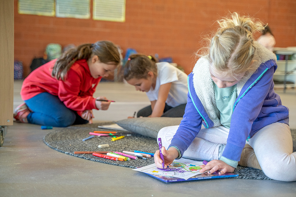 Children sitting on floor mats drawing and colouring during quiet creative time at Kalgoorlie OSHC School Holiday Program