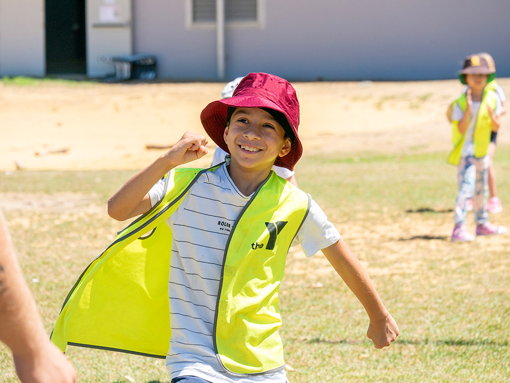 Smiling child in hat running during Coles Healthy Kicks activity at Kalgoorlie OSHC School Holiday Program