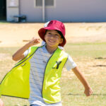 Smiling child in hat running during Coles Healthy Kicks activity at Lake Gwelup OSHC School Holiday Program