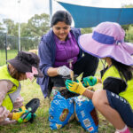 Children and educator collaborating on potting plants during Riverton OSHC School Holiday Program
