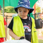 Child brushing sheep at Old Macdonald's Travelling Farm during Sacred Heart OSHC School Holiday Program