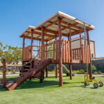 Large timber climbing fort with slide on artificial turf at Kalgoorlie childcare centre