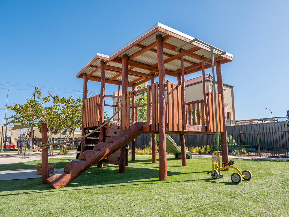 Large timber climbing fort with slide on artificial turf at Kalgoorlie childcare centre