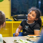 Smiling child making sushi with friends during cooking activity at Gumtrees OSHC School Holiday Program