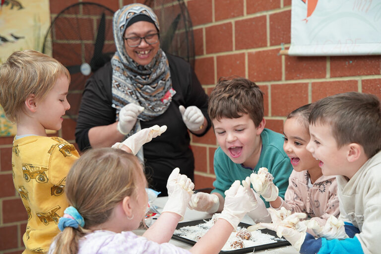 Children and OSHC Supervisor Ennity Lumsden engaging in cooking activity at Huntingdale OSHC School Holiday Program