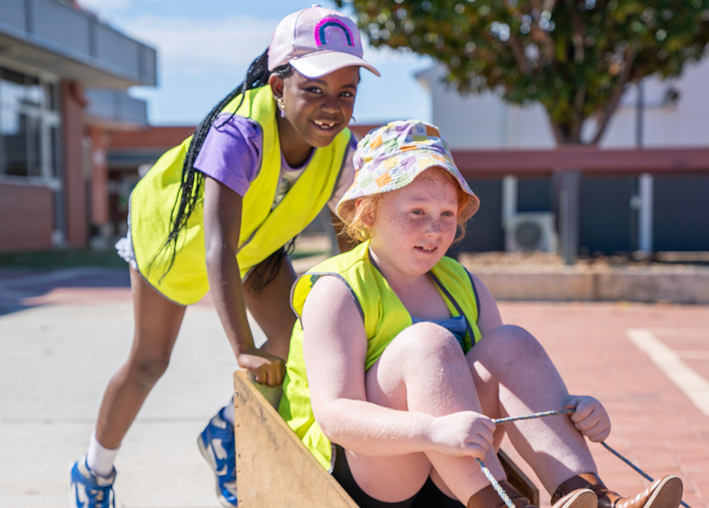 Child pushing another child on a go-kart during Mercy OSHC School Holiday Program