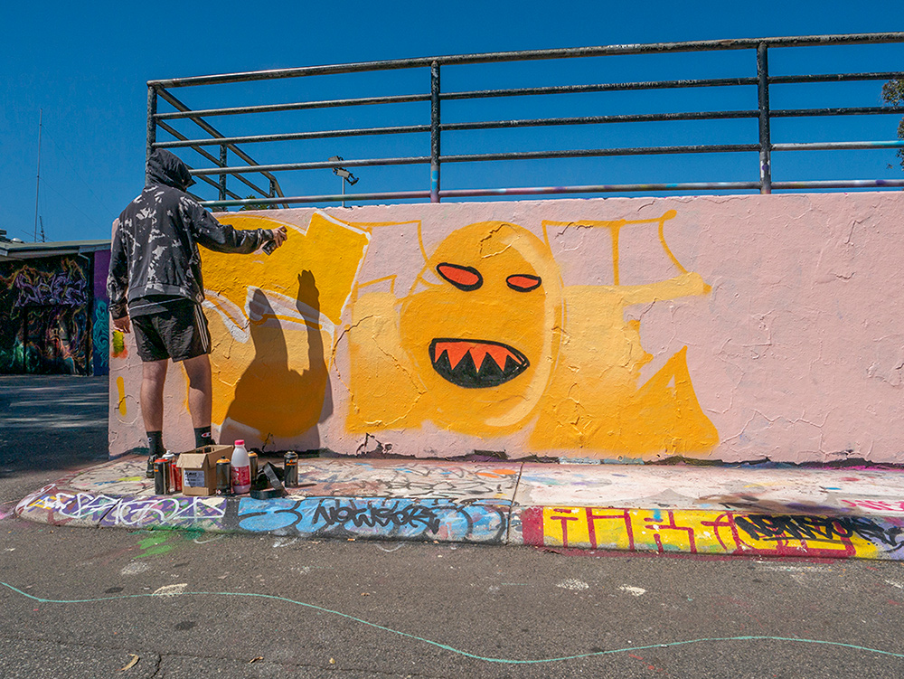 Street artist painting a street art mural with spray paint