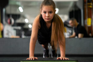Full shot of young person doing push ups and training in the gym