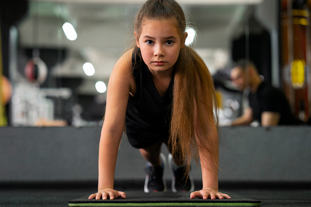 Full shot of young person doing push ups and training in the gym