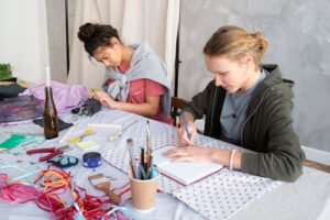 Two young girls painting and doing crafts on a table together