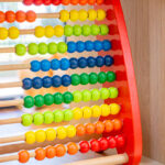 A close-up of a colourful rainbow abacus with rows of red, orange, yellow, green and blue beads on wooden rods