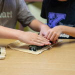 Two children making sushi together during cooking activity at OSHC