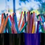 Close-up of colourful markers and textas in pencil holders at OSHC art station