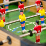 Close-up of foosball table player figures on green pitch at OSHC games area