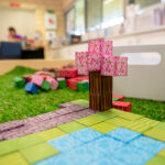 A Minecraft-themed paper craft scene featuring a cherry blossom tree, stone path, and grass tiles