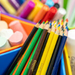 Close-up of Crayola coloured pencils, erasers, and glue sticks sorted into colourful plastic trays