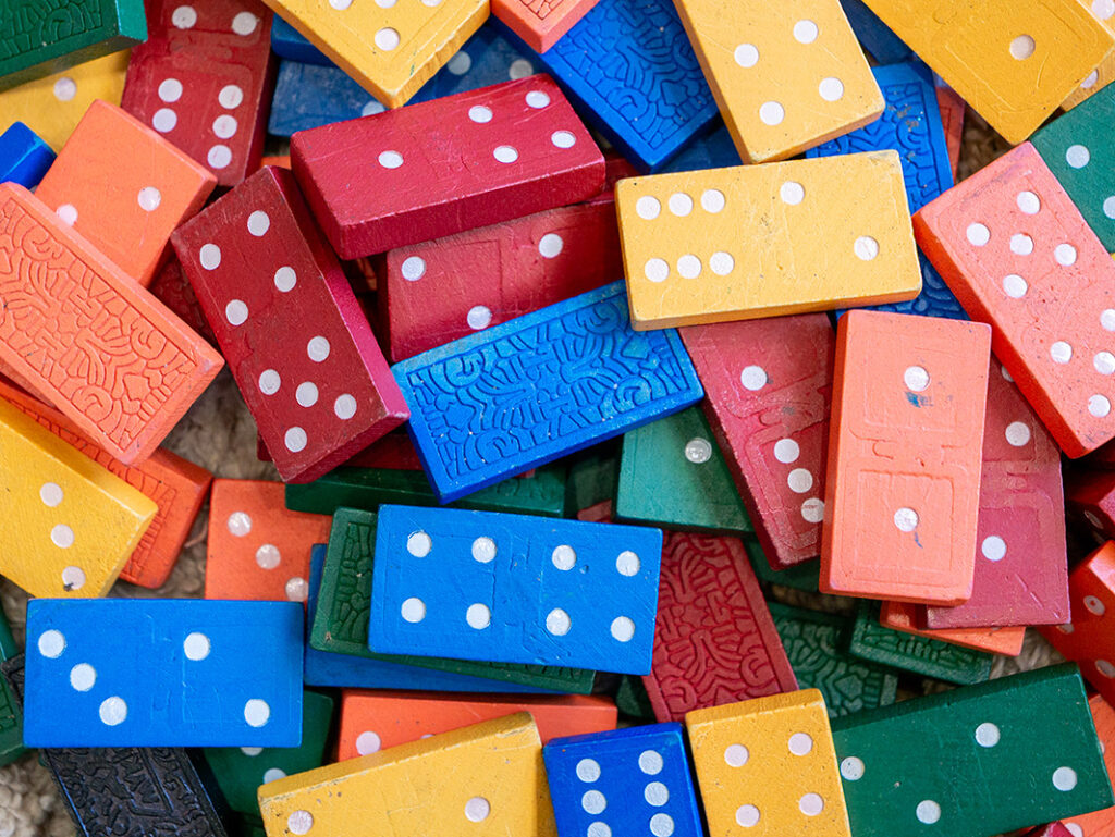 A pile of colourful wooden dominoes in red, blue, yellow, orange, and green scattered together