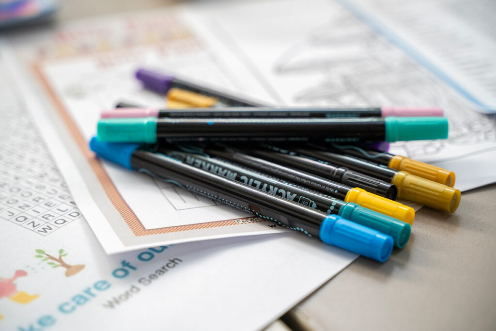 Close-up of Crayola coloured pencils, erasers, and glue sticks sorted into colourful plastic trays.