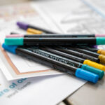 Close-up of Crayola coloured pencils, erasers, and glue sticks sorted into colourful plastic trays.