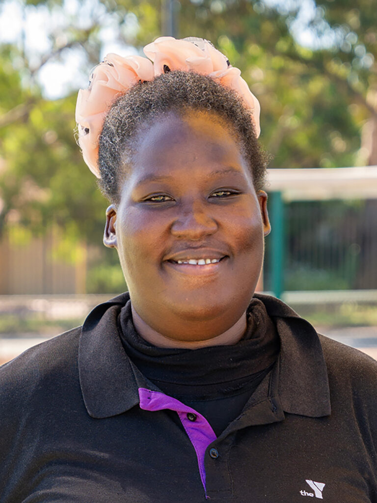 Smiling childcare educator in Y WA uniform at outdoor playground
