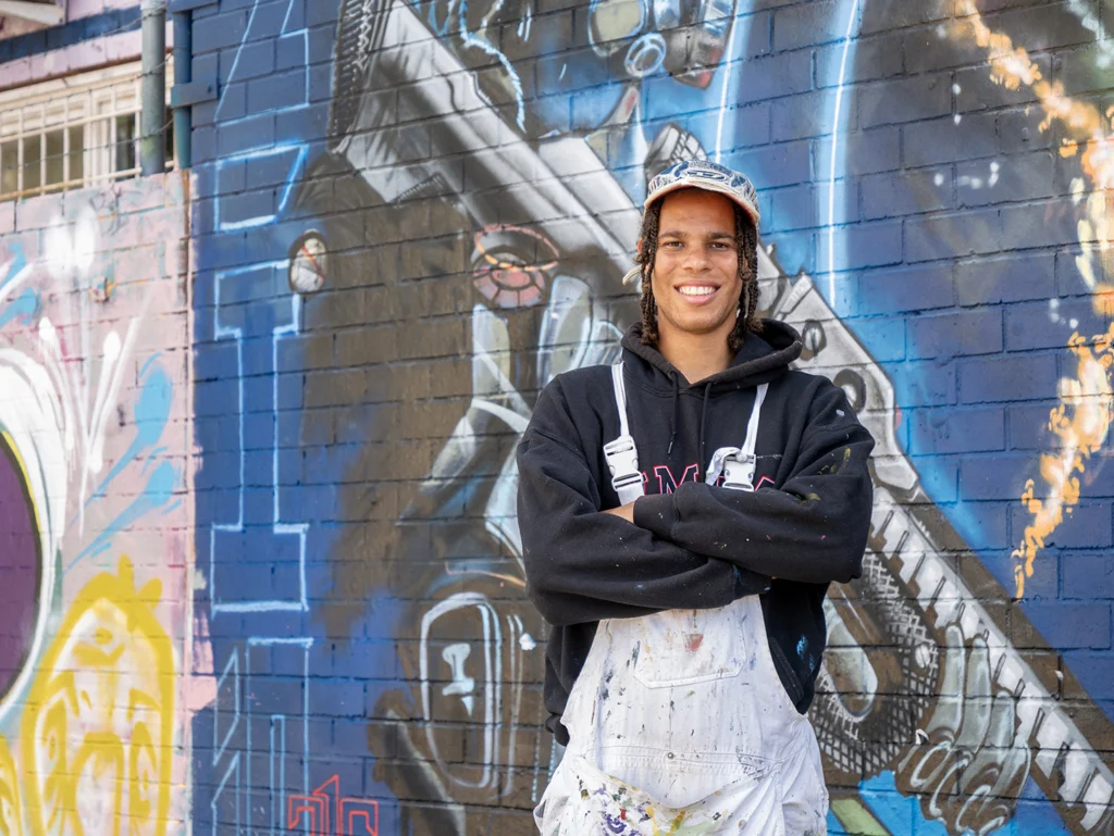 Young artist standing in front of street art outside