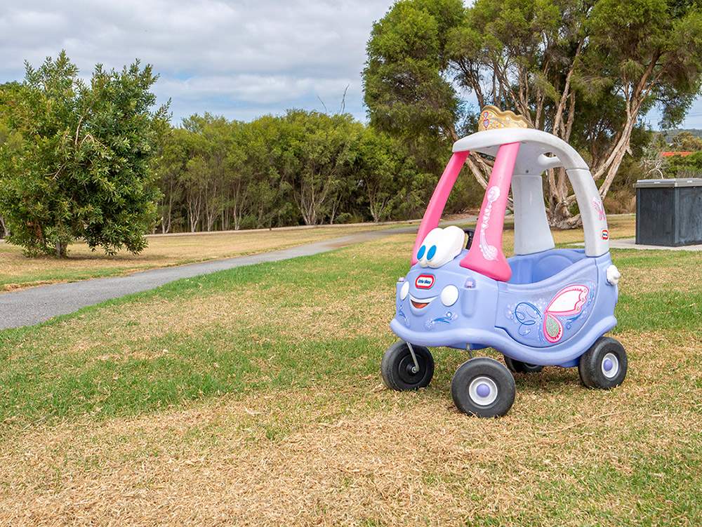 A Little Tikes princess coupe ride-on toy car sitting on grass in a park