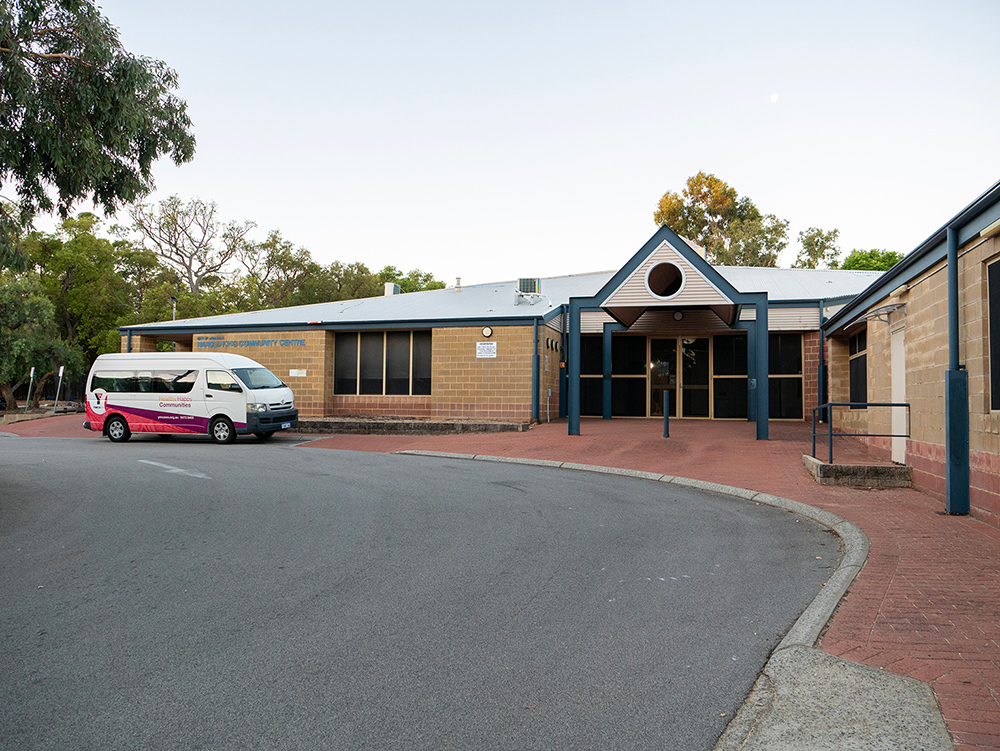 Front exterior of the Harold King Community Centre with a YMCA Communities van parked outside, surrounded by gum trees