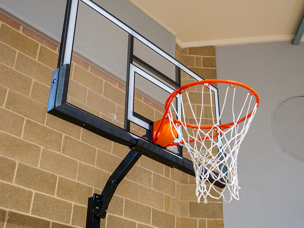 Close-up of an indoor basketball hoop and backboard mounted against a brick wall
