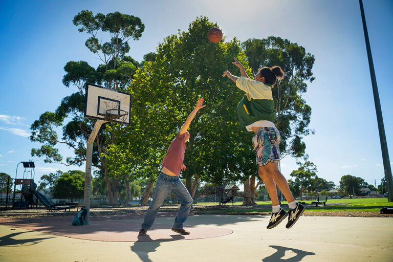 Two young people playing basketball on an outside basketball court